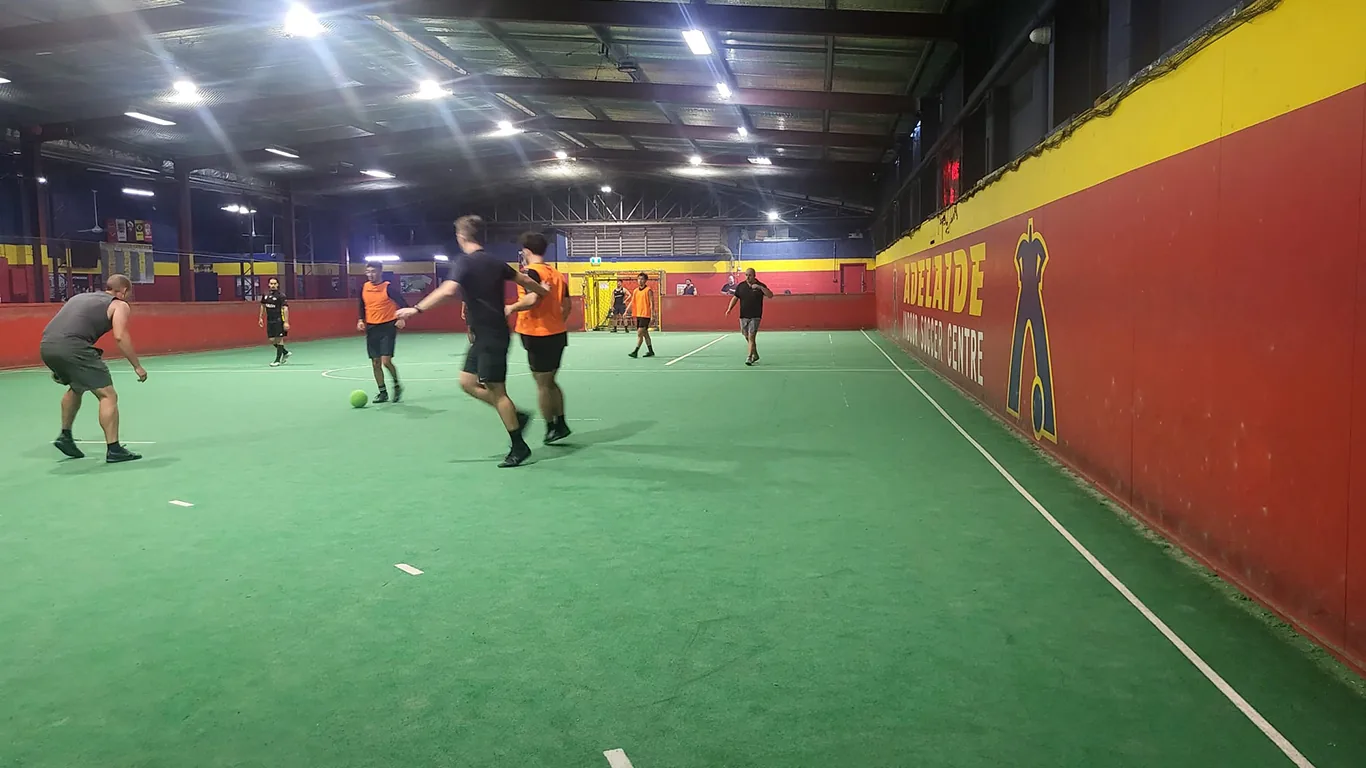 Adults playing on the netted indoor soccer court at Adelaide Indoor Sports Centre