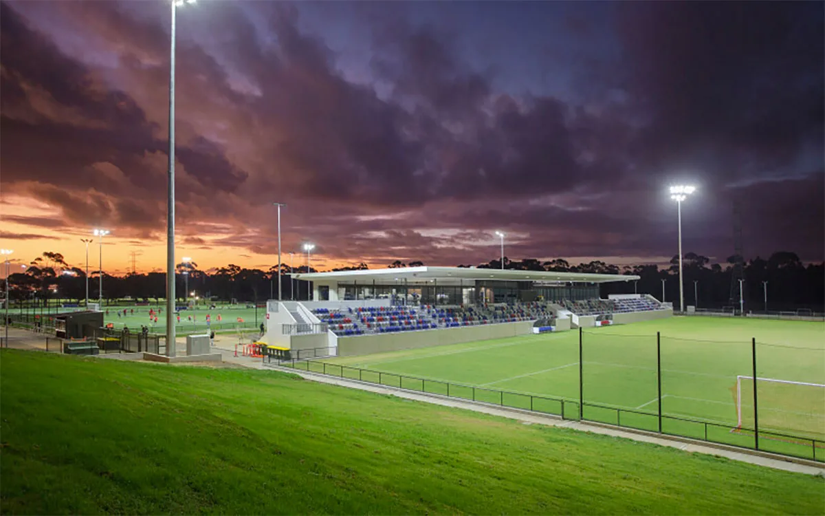 Floodlit pitch and grandstand at ServiceFM Stadium, Gepps Cross, at dusk