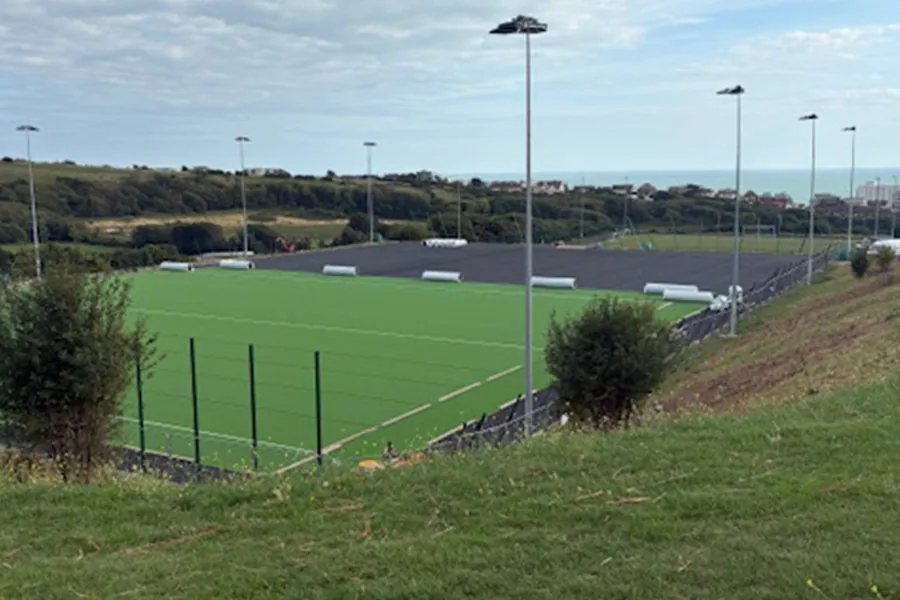 Outdoor pitches at Stanley Deason Leisure Centre during resurfacing, with the sea beyond